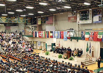 Graduates in caps and gowns and the stage at commencement are shown. 
