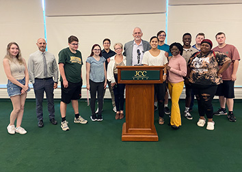 A group of students stand with retired SUNY JCC Professor Greg Rabb after hearing him speak at Citizenship Day.