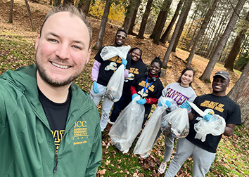 A man takes a selfie with a group of SUNY JCC students outdoors.