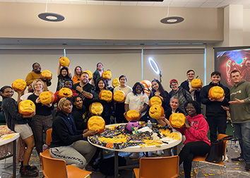 Students stand with Eric Jones and holding the pumpkins he taught them to carve.