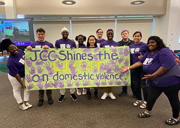 A group of students stand with a banner they made at a recent Shine the Light event.