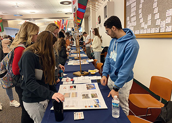 Students surround tables where international students at SUNY JCC are sharing information about their home countries.