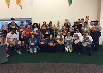 Students pose with paintings they created during a workshop on the SUNY JCC Jamestown campus.