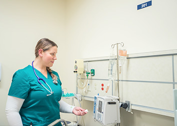A nurse checking medical equipment in a hospital-type setting.