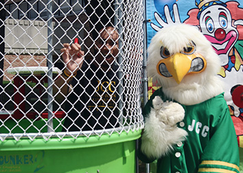 JJ Jayhawk stands near a dunking tank with a person inside.