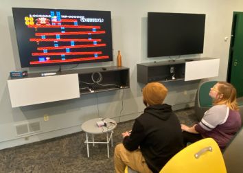 Two people look at tv screen and play a video game.