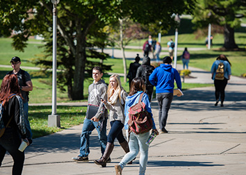 Students walking on a sidewalk on a college campus.