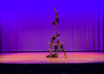 Acrobats perform a contortion on a stage with a curtain backdrop