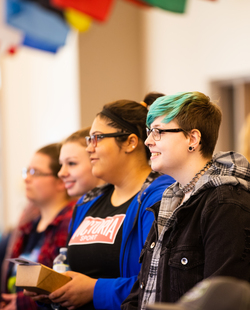 Students watching an event under the international flags in the Student Union at SUNY Jamestown Community College.