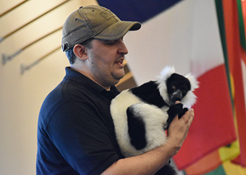 A man wearing a hat holds a furry exotic animal.
