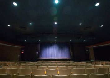A lit theatre stage viewed from behind the seats in the the theater.