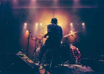 A picture of a person on a drum set with professional lights in the background