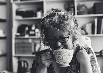 An image of a woman smiling over a cup of tea.