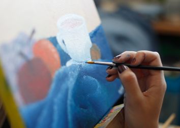 The hand of an artist painting on a colorful canvas.