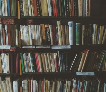 Many books stacked on a bookshelf.
