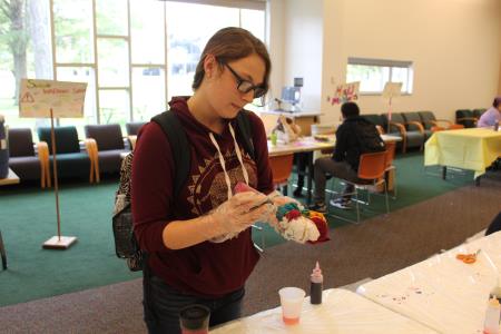 A student squeezes paint onto a shirt while making a tie dye T-shirt.