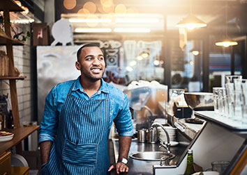 A man with an apron smiling in a coffee shop