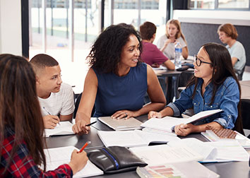 A group of students circled around a table working on a paper