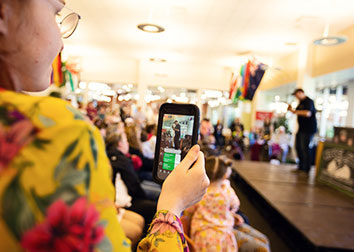 Student records a performer on stage using a phone. 