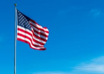 An American flag flies with a blue sky in the background.