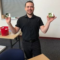 A student holding up two coasters he painted at an event