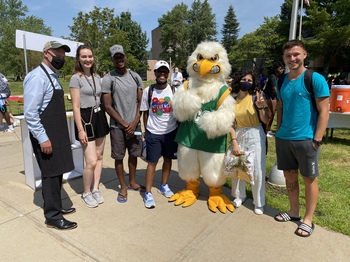 A group of students stands with JJ Jayhawk and SUNY JCC President Daniel DeMarte, who is wearing a black apron.,