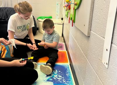 A child plays with an adult in an occupational therapy setting.