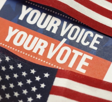 Patriotic election graphic reading “YOUR VOICE YOUR VOTE,” layered over red, white, and blue American flag patterns, conveying civic pride.