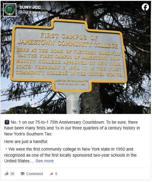 A sign marking the first campus of Jamestown Community College stands on a metal post. It's surrounded by trees and contains text commemorating the site.