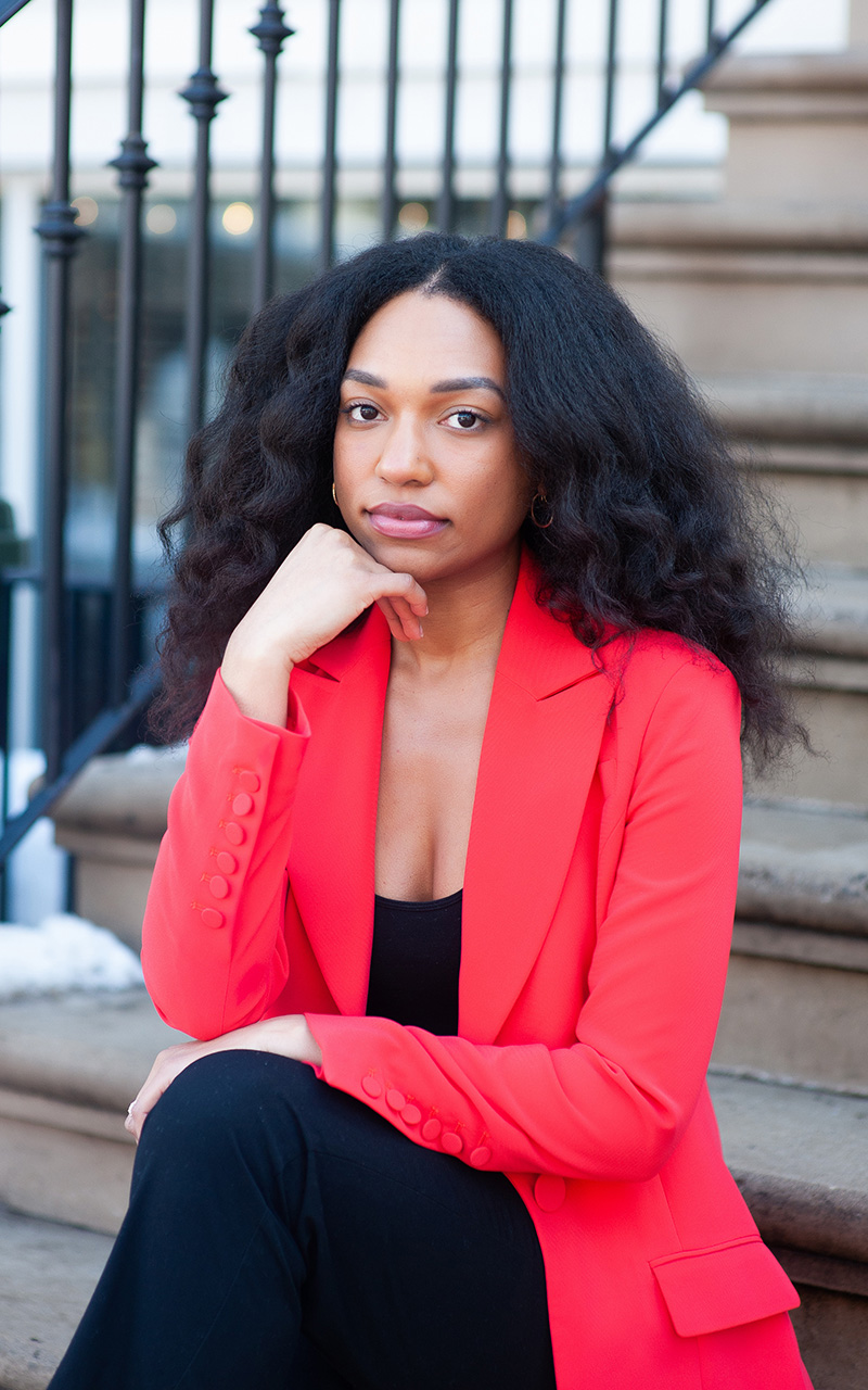 A woman seated on steps with her closed fist beneath her chin.