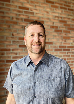A man standing in front of a brick wall.