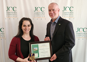 Stephanie Cardone and Daniel DeMarte stand in front of a SUNY Jamestown Community College backdrop holding Stephanie's Chancellor's Award.