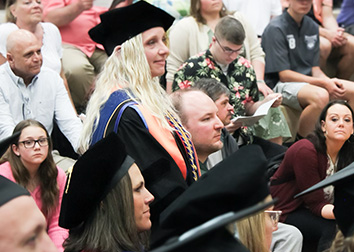 Dr. Renee Funke stands among the audience during SUNY Jamestown Community College's commencement ceremony as she is presented with the Chancellor's Award for teaching.