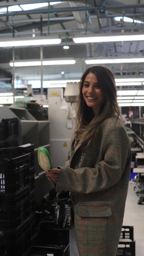 Woman holding a high heel inside a footwear manufacturing plant.