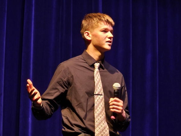 A student speaks into a microphone he is holding.