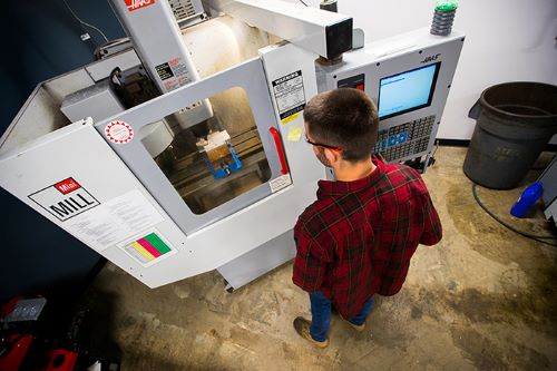 An overhead view of a student working with CNC machining equipment.