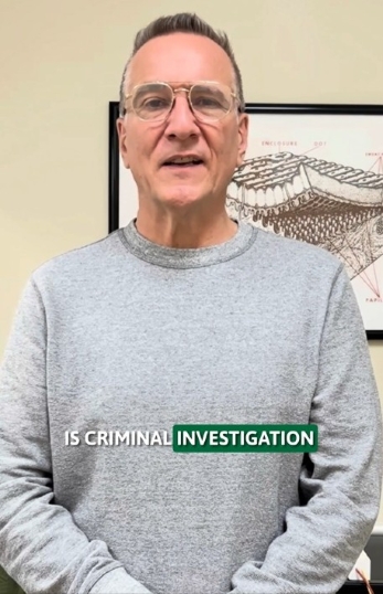 A person in a gray sweatshirt stands in front of a framed anatomical diagram. They wear glasses and have a neutral expression. The text overlay reads, "Is Criminal Investigation."