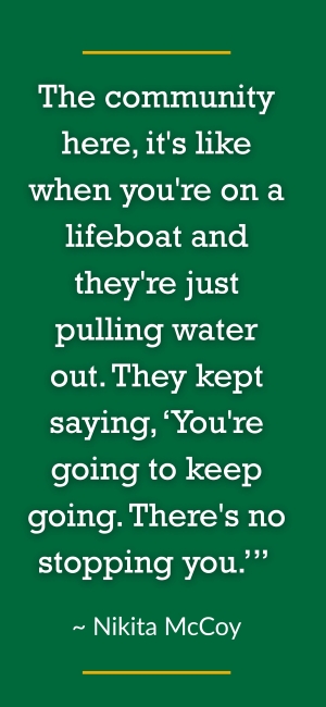 A smiling person with long hair is on the right. On the left, a green panel displays a motivational quote about perseverance and community support said by Nikita McCoy: "The community here, it's like when you're on a lifeboat and they're just pulling water out. They kept saying, ‘You're going to keep going. There's no stopping you.’” 