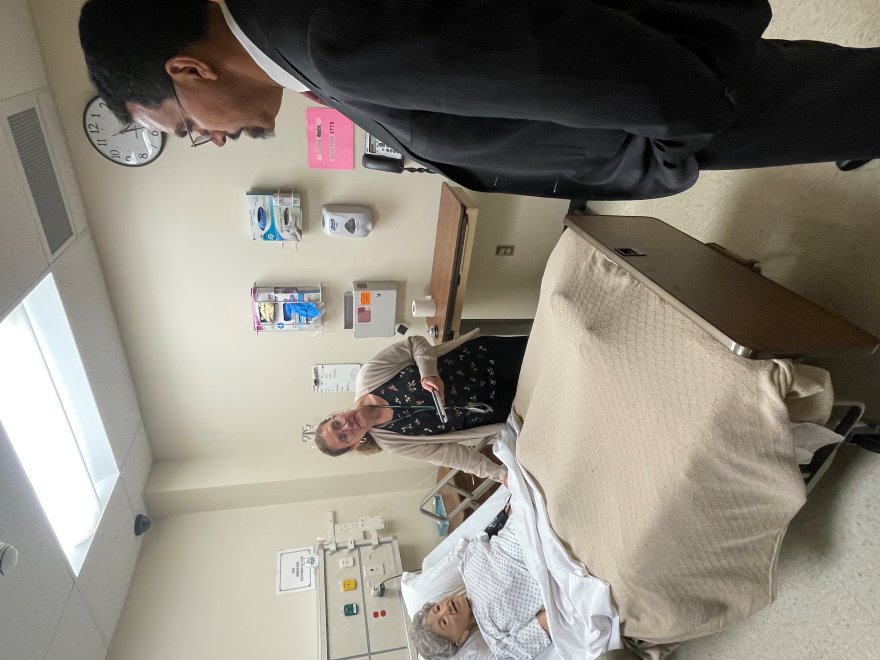 A woman gives a nursing a demonstration on a mannequin while a man looks on.
