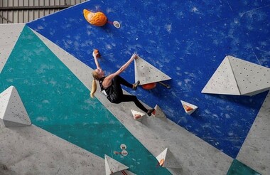 A woman climbing on an indoor rock climbing wall.