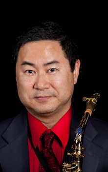 A headshot of saxophonist Andy Wen, holding a saxophone.