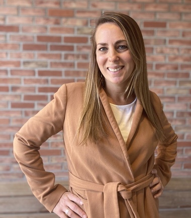 A woman standing in front of a brick wall.