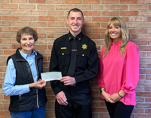 Verna Feather, Recruit Aaron Pacos, and Raechel Waid stand together, holding scholarship check