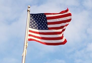 American flag waving with a blue sky in the background.
