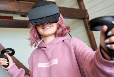 A person wearing a VR headset with motion controllers in her hands.