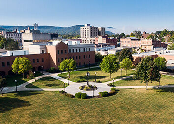 A drone image of the Cattaraugus County Campus that shows a circular sidewalk that radiates out in four directions, surrounded by street lamps, trees, and buildings.