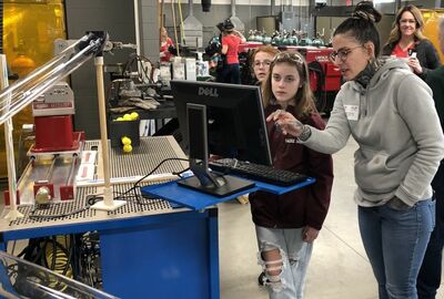 People look at a computer screen inside a college manufacturing learning space.