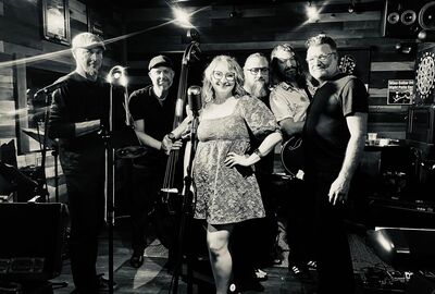 A group of people stand together under spotlights holding musical instruments.