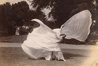 Loie Fuller dancing outdoors while swinging around her large white dress.