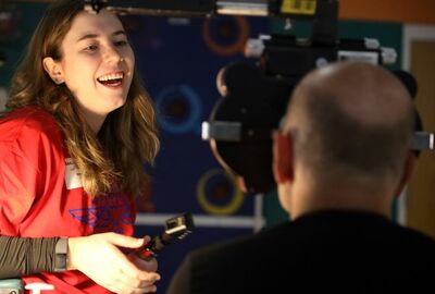 A woman giving an eye exam to a man smiles.